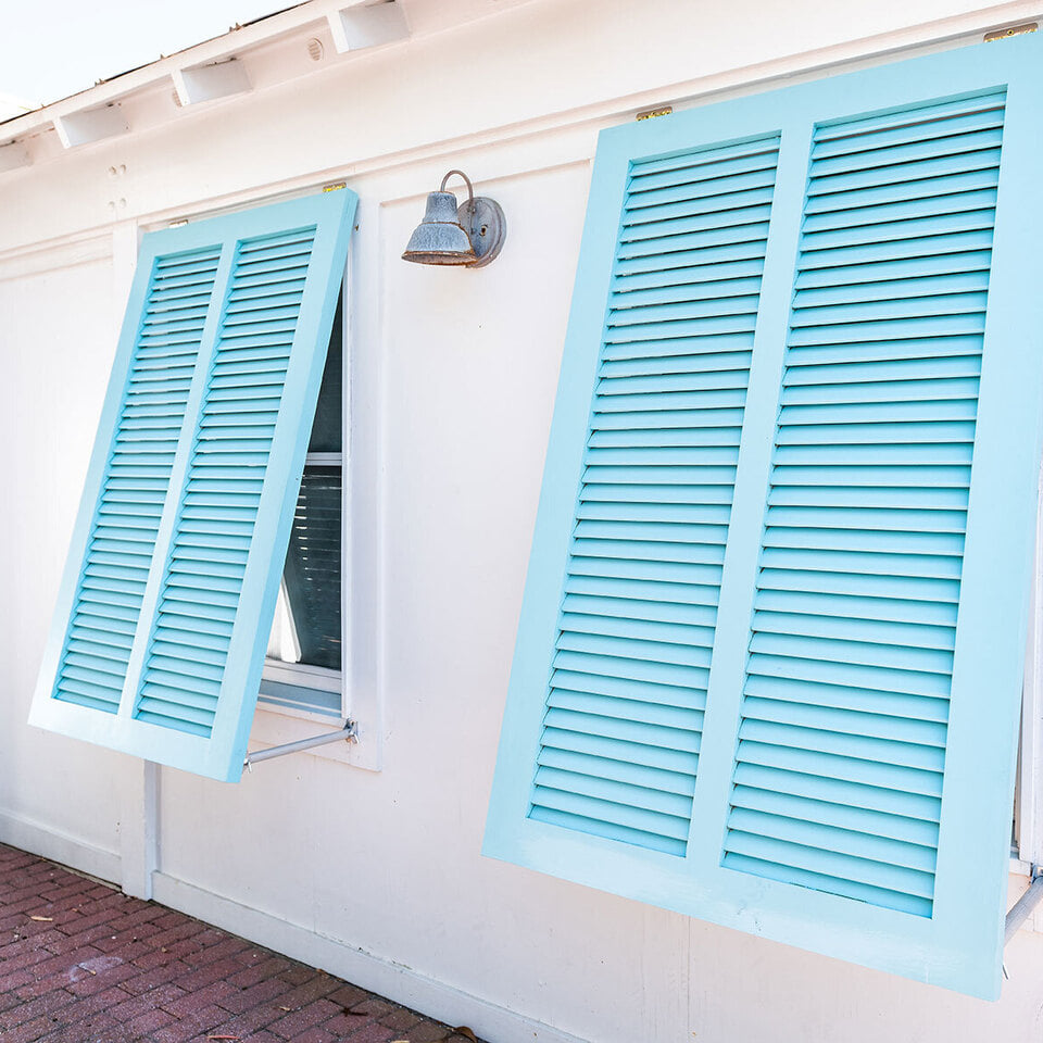 Light blue Bahama hurricane shutters on a coastal home